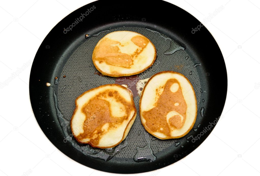 Fritters on a frying pan pancakes on the griddle on the white isolated back