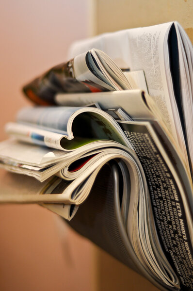 Складные и скомканные газеты и журналы в кронштейне
