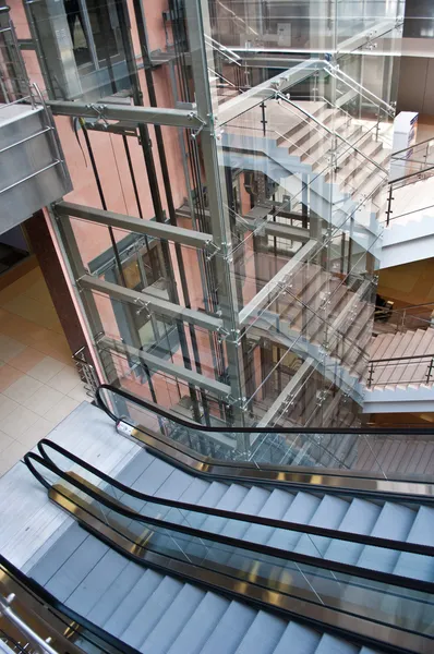 Arbres d'ascenseur en verre et escaliers mécaniques dans un immeuble de bureaux moderne — Photo