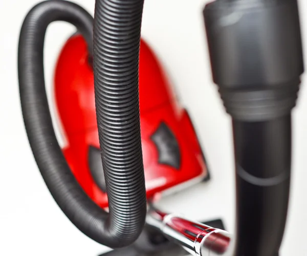 L'aspirateur rouge avec un tuyau noir sur fond blanc — Photo