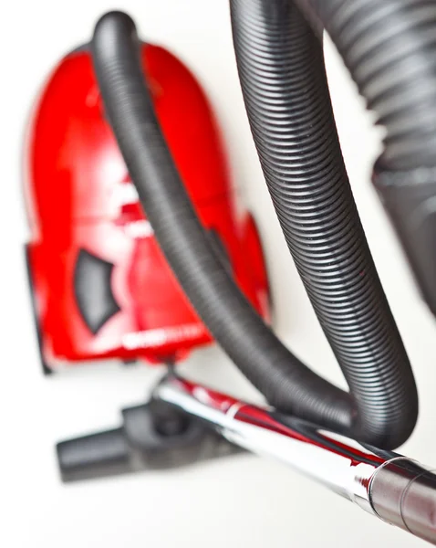 stock image The red vacuum cleaner with a black hose on a white background