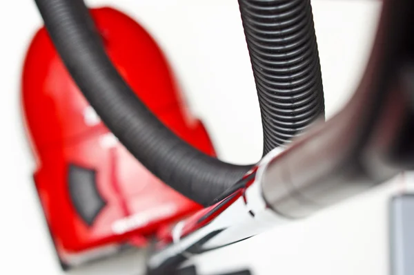 Beyaz bir arka plan üzerinde siyah bir hortum ile kırmızı elektrikli süpürge — Stok fotoğraf