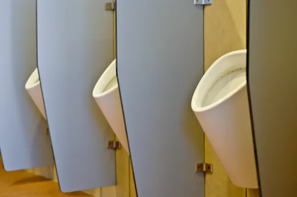 Urinoirs achter partities in een toilet in kantoorgebouw — Stockfoto