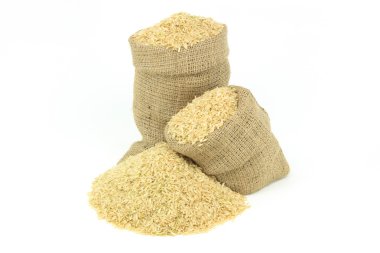 Still picture displaying brown rice spilled on pile and in burlap sacks over white background. clipart