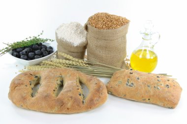 Loaf Mediterranean Ciabatta and Fougasse black olive breads, wheat ears, wheat kernel and whole wheat flour in burlap sacks, olives, olive oil, over white backg clipart