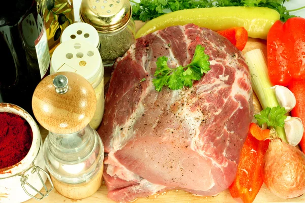 Cut pork meat with added black pepper and ready for adding different ingredients, oil, vegetables and red wine.