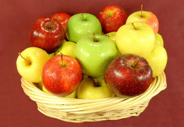 Ассорти яблоки в корзине на красном фоне . — стоковое фото
