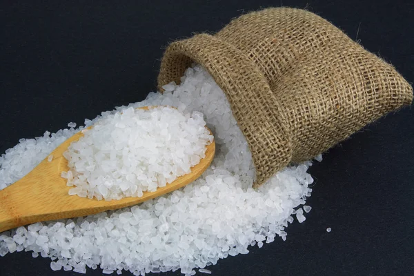 Rozlane soli kamiennej i nad drewnianą łyżką. — Zdjęcie stockowe