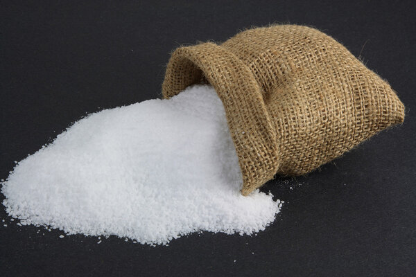 Picture of Spilled Pickling Salt, which is fine grain not iodine sea salt, from Burlap sack over black background.