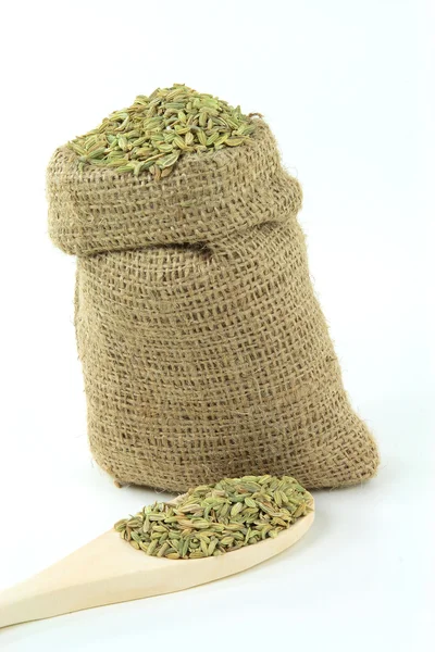 Sementes de erva-doce em saco de serapilheira e colher de madeira . — Fotografia de Stock