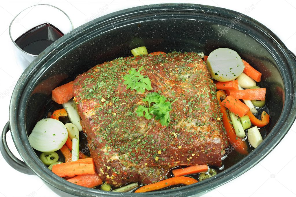 Cut pork meat with added ingredients and vegetables, ready red wine to be added and to be roasted in the oven.