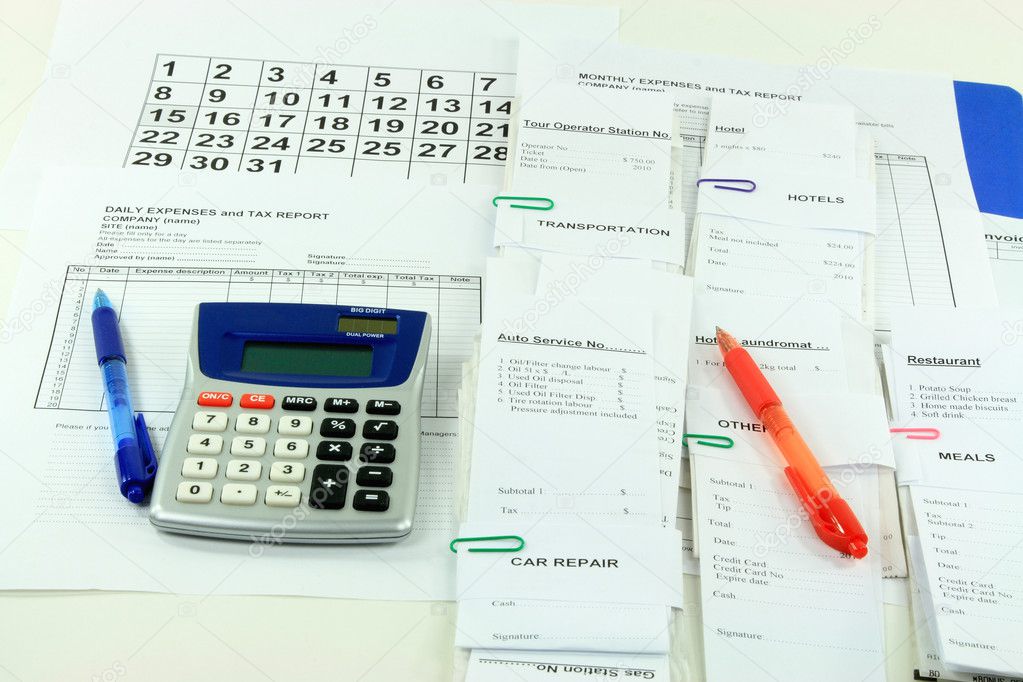 Picture of all expense report forms, daily and monthly, electronic calculator, pens and bills used to finalize financially the month - getting ready to fill dow