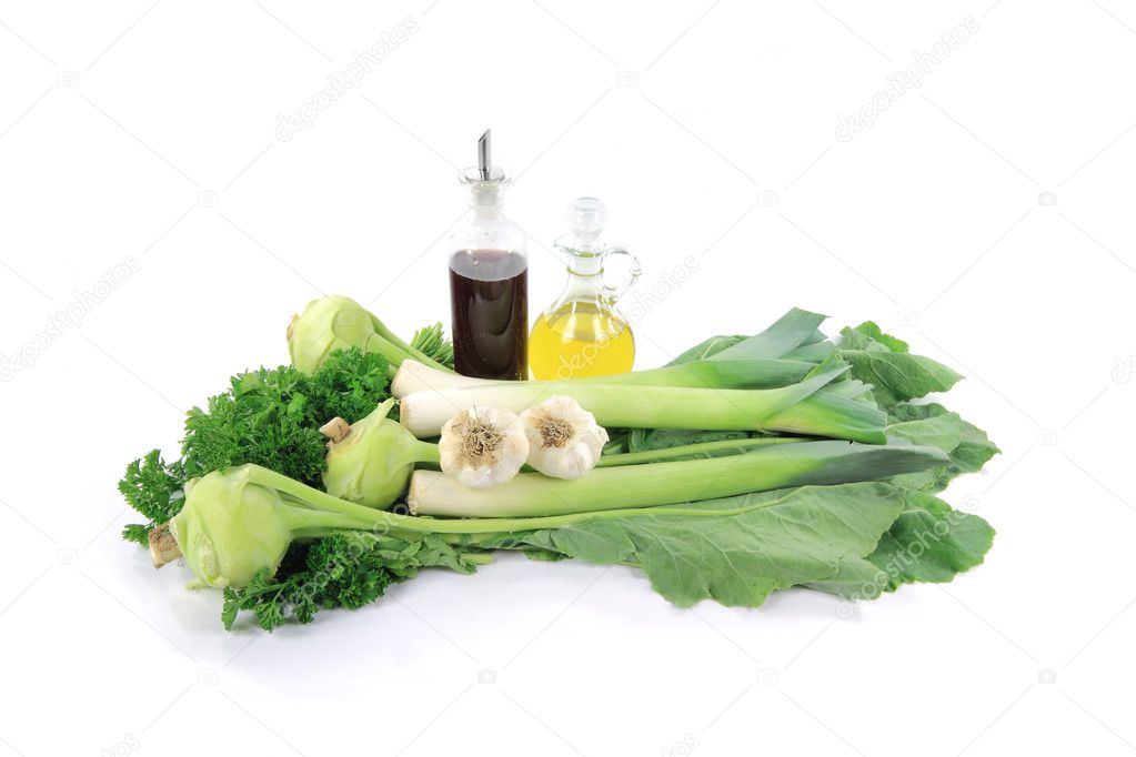 Still life picture of Green vegetables (Green Kohlrabi, Leeks), ingredients (Garlic) and seasonings (Curly Parsley, Wine Vinegar, Olive Oil) over white backgrou