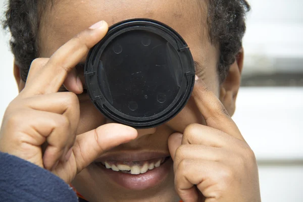 Niño jugando con una cubierta de lente — Foto de Stock