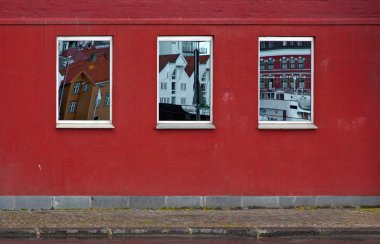 Stavanger, Norveç şehir merkezinde bulunan bir kırmızı boyalı tuğla duvar. Windows binalar ve karşı tarafta liman gemi yansıtacak.