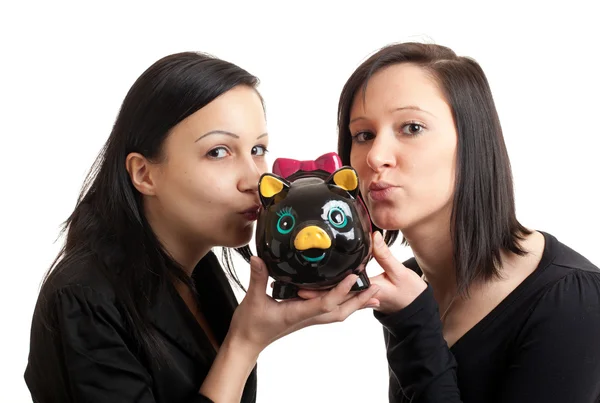 Twee jonge vrouwen piggy bank kussen — Stockfoto