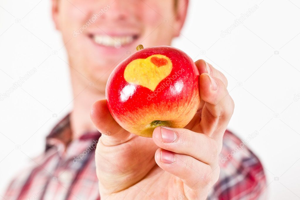 A Man is holding a red Apple with two Hearts on it