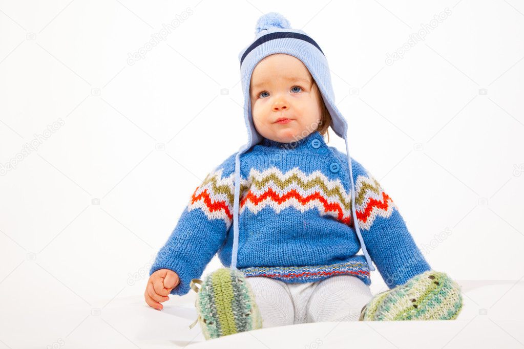 Young Kid is sitting in Studio with Winter Clothes and Hat.