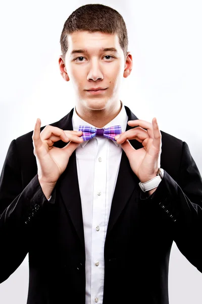 Young man in tuxedo with singlasses fixing bow tie — Stock Photo, Image