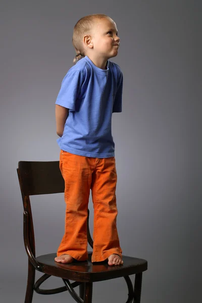 stock image Funny kid on chair in studio on grey background