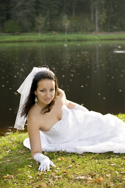 Noiva deitada ao lado da lagoa — Fotografia de Stock