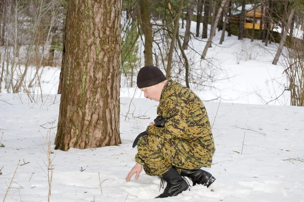 Stock image Hunter or soldier squatted for examining footprints