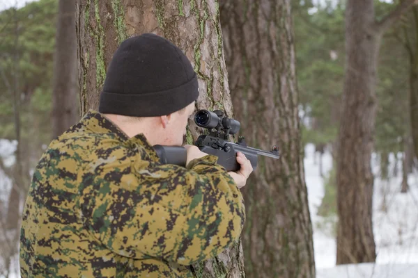 Hunter takes aim from behind a tree — Stock Photo, Image