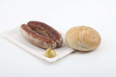 A pair of fried sausages with mustard, zwei Bratwürste mit Senf und Brötchen auf einem Pappteller clipart