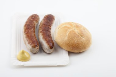 A pair of fried sausages with mustard, zwei Bratwürste mit Senf und Brötchen auf einem Pappteller clipart