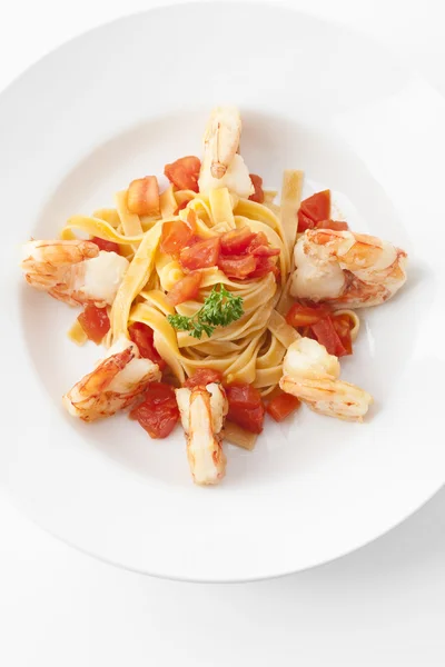 stock image Garnelen mit Tomaten auf einem Tagliatelle-Nest, king prawns with italian pasta