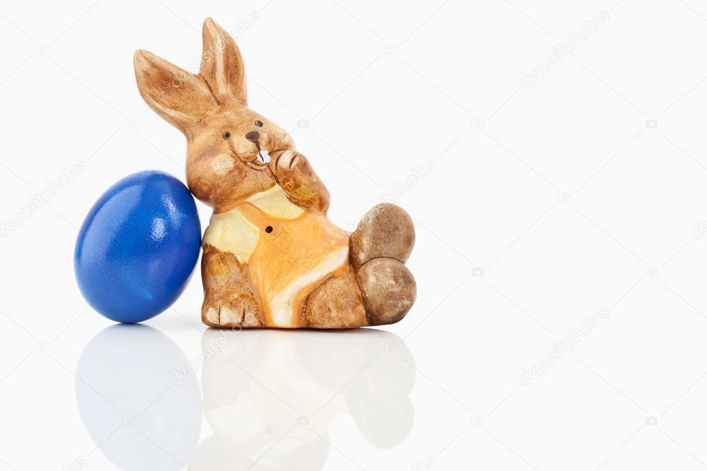 A easter bunny is sitting next to a colored egg