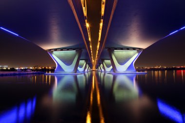 The Al Garhoud Bridge in Dubai crosses the Creek and is illuminated at night clipart