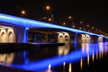 The Business Bay Crossing in Dubai crosses the Creek and is illuminated at night clipart