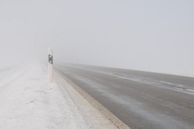 Landstraße im Nebel bei Winterwetter mit Schnee