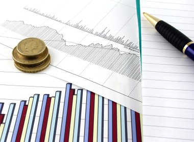 Business chart and graphs, with a notepad and pen beside clipart