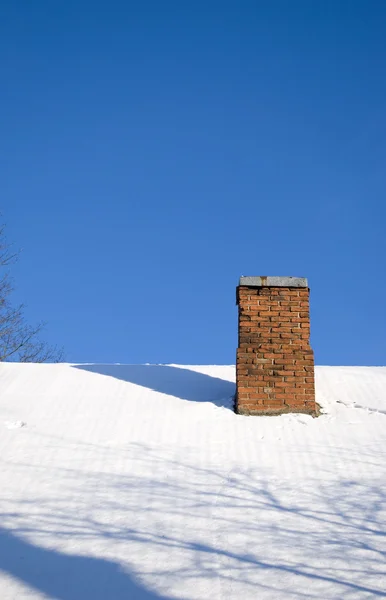Techo cubierto de nieve y chimenea de ladrillo rojo — Foto de Stock