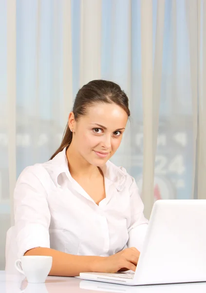 Jovem mulher de negócios trabalhando no laptop no interior branco — Fotografia de Stock