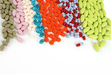 Many different pills lined up on a white background. clipart