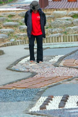 A Korean woman walks on rocks. clipart