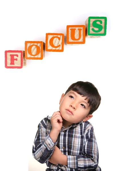 stock image A concept image of a young boy under the word blocks that says focus.