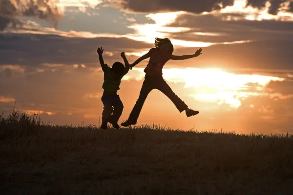 Kids jumping at sunset. — Stock Photo, Image