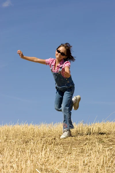 一个年轻的女孩昂首阔步已收获的小麦字段中 — 图库照片