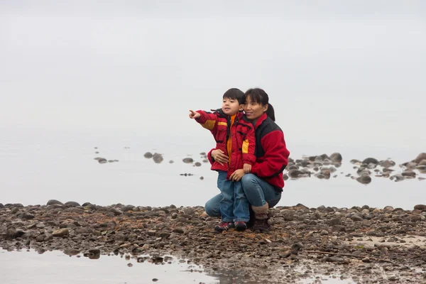 母と彼女の幼い息子は湖で岩が多い海岸線です — ストック写真
