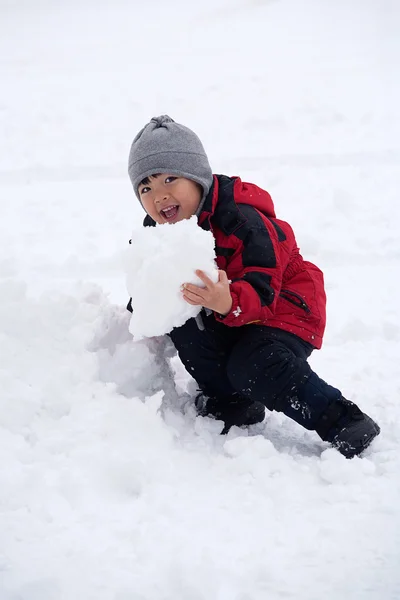 彼は雪の大きな塊を食べるしようとしているようなふりをする少年 — ストック写真