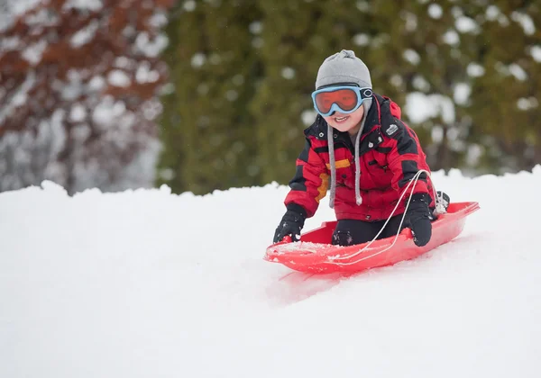 一个年轻男孩显示山脚下雪橇在冬天他兴奋 — 图库照片