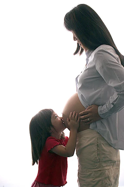Happy girl kisses mommys tummy. — Stock Photo, Image