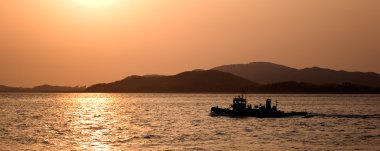 A panorama image of a fishing boat at sunset off the coast of Inchon, Korea. clipart