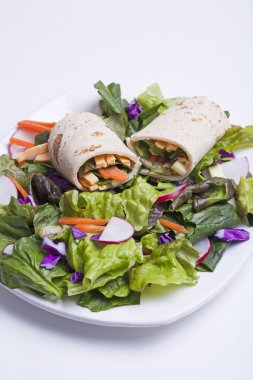 A veggie wrap with fresh veggies and veggie cheese on top of a salad. clipart