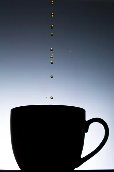Kaffee Tropft Vor Abgestuftem Hintergrund Die Silhouette Einer Kaffeetasse — Stockfoto