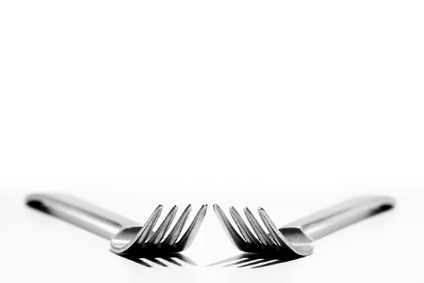 stock image Two forks angled towards each other on a white back ground